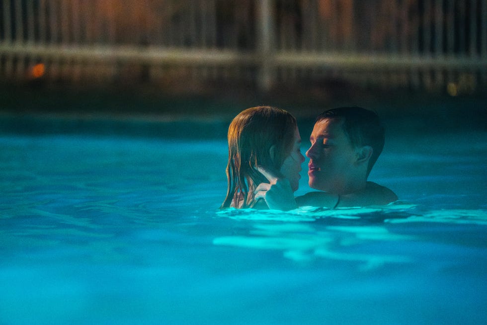 Two individuals embracing in a pool at night visible water ripples and soft lighting