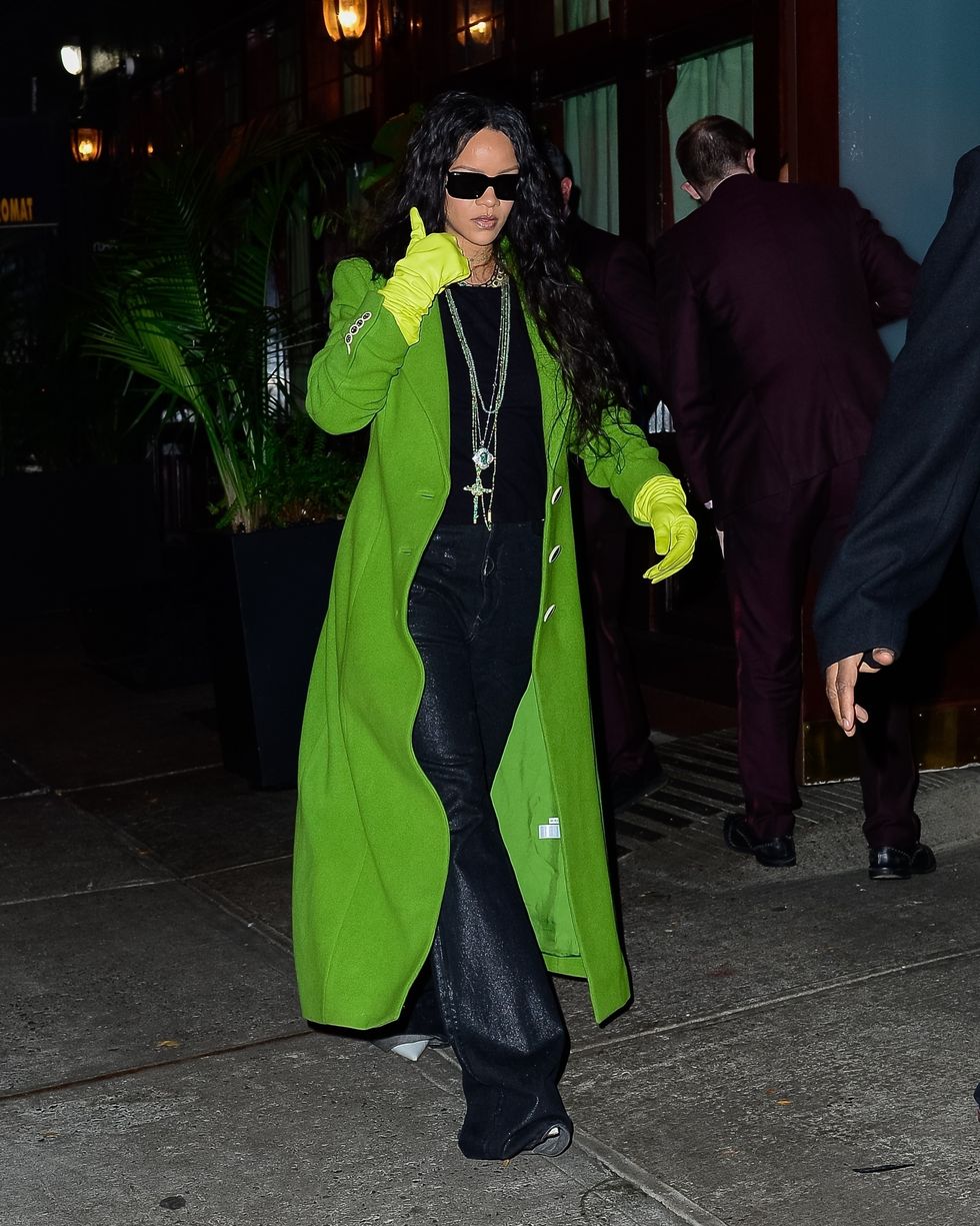 rihanna walks down sidewalk in green coat and green gloves and black outfit