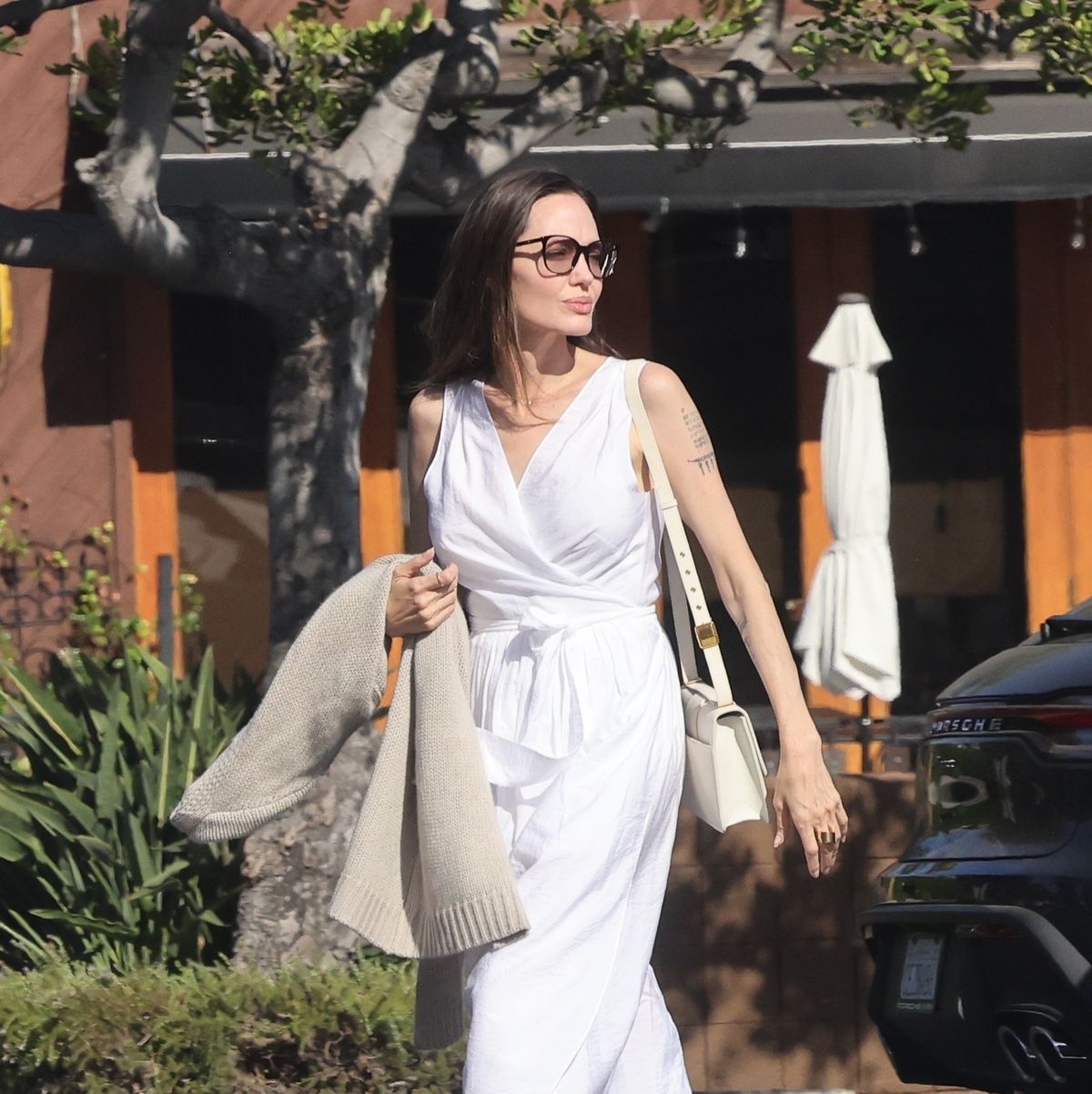 Angelina Jolie keeps it classy in a white dress and black jacket as she  touches down