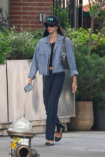 model kaia gerber wearing low rise pants, a chambray jacket, and a brat hat referencing charli xcx in new york city
