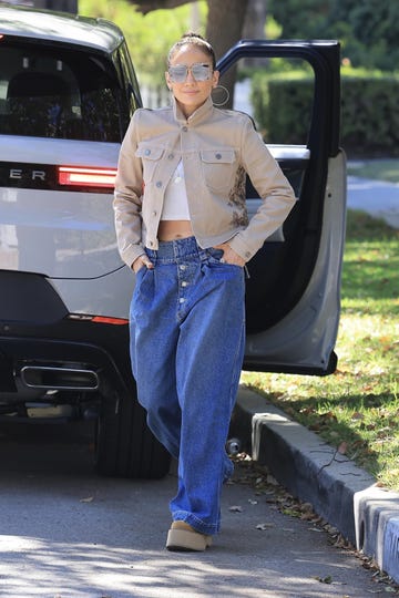 jlo walks down a road with her hands in her pockets