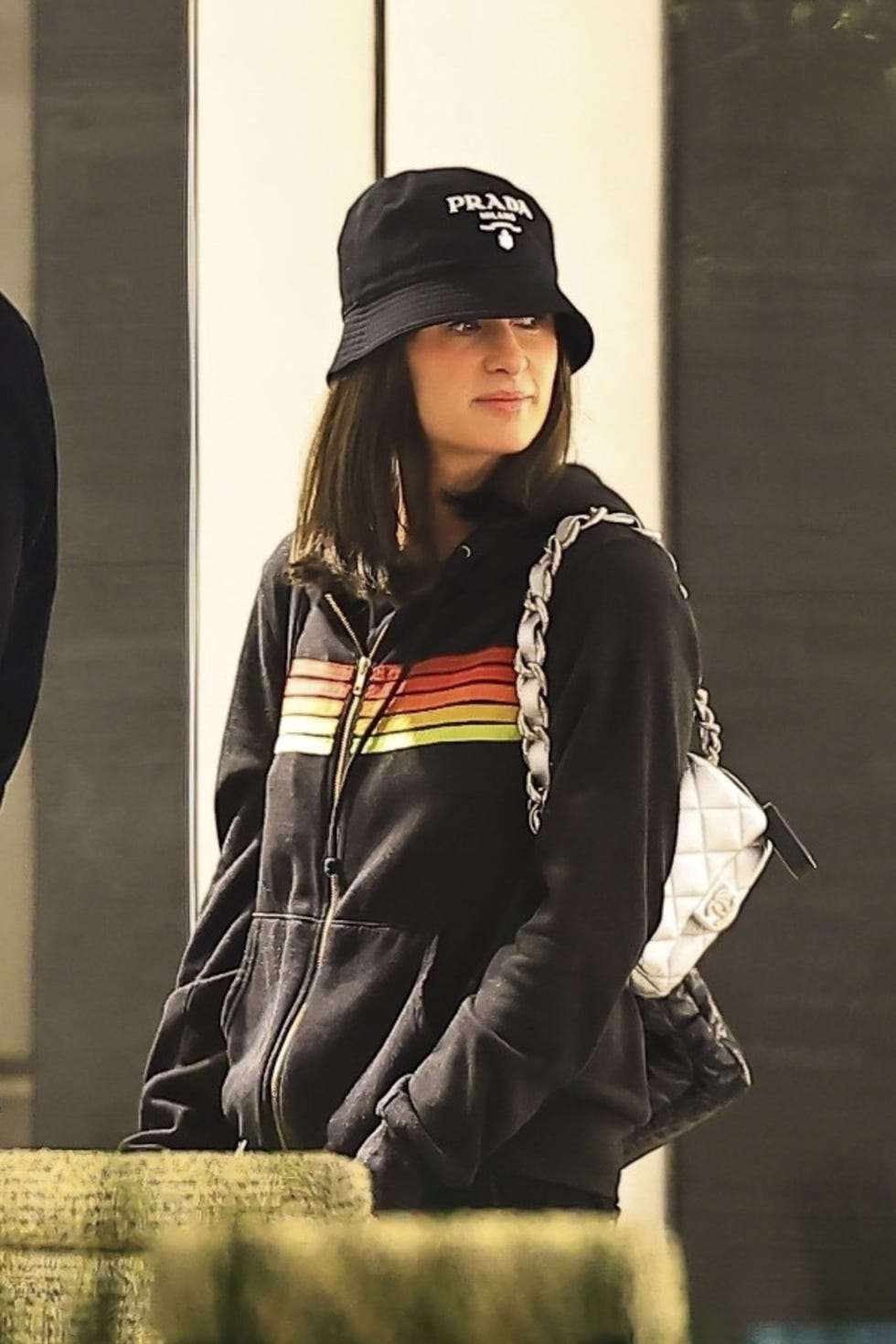 person wearing a black hoodie and bucket hat holding a handbag