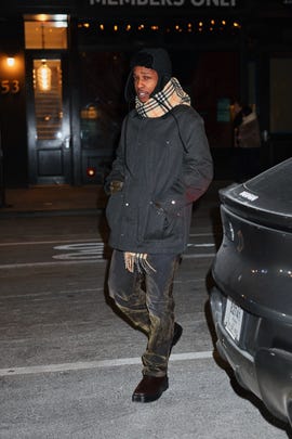 person in winter attire walking near a parked car at night