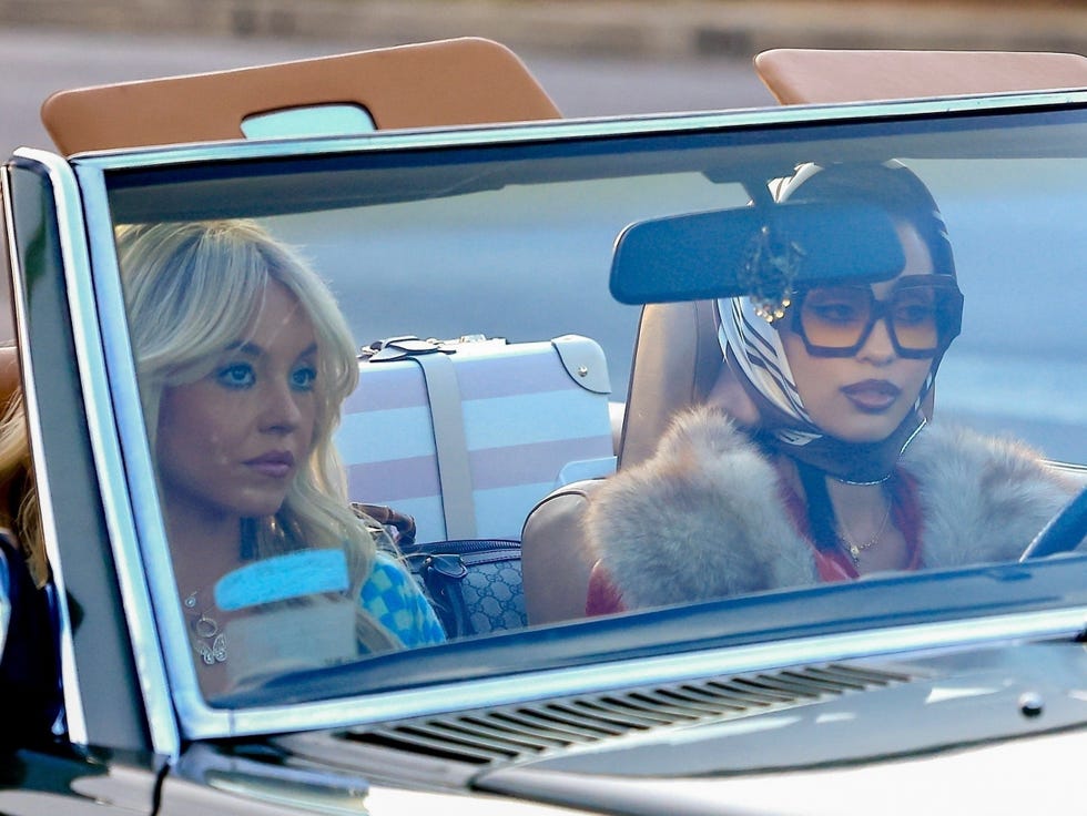 two women in a convertible car with visible luggage in the back seat