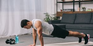 bi racial man doing push ups in sportswear on  fitness mat