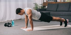 bi racial man doing push ups in sportswear on  fitness mat