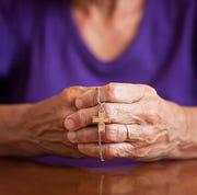 bible verses about anxiety woman with hands together holding a necklace with a cross