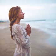 bible verses for women woman holding hands together in prayer on a beach