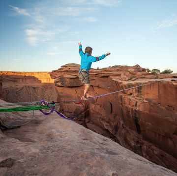 Guy walking on a line over a canyon in Moab.