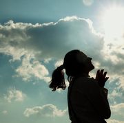 bible verses about faith silhouette of woman holding hands in prayer and looking up towards sky full of clouds