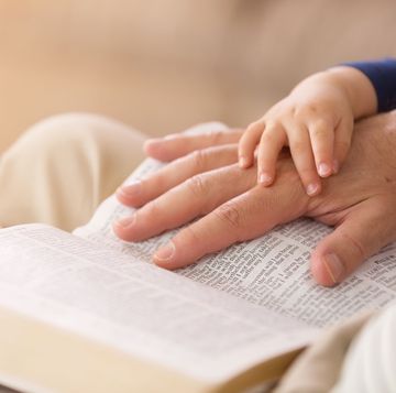 hand of a father and hand of a baby on the bible