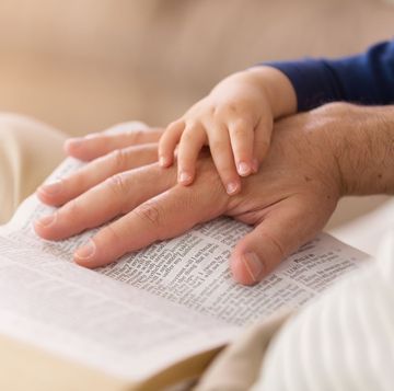 hand of a father and hand of a baby on the bible