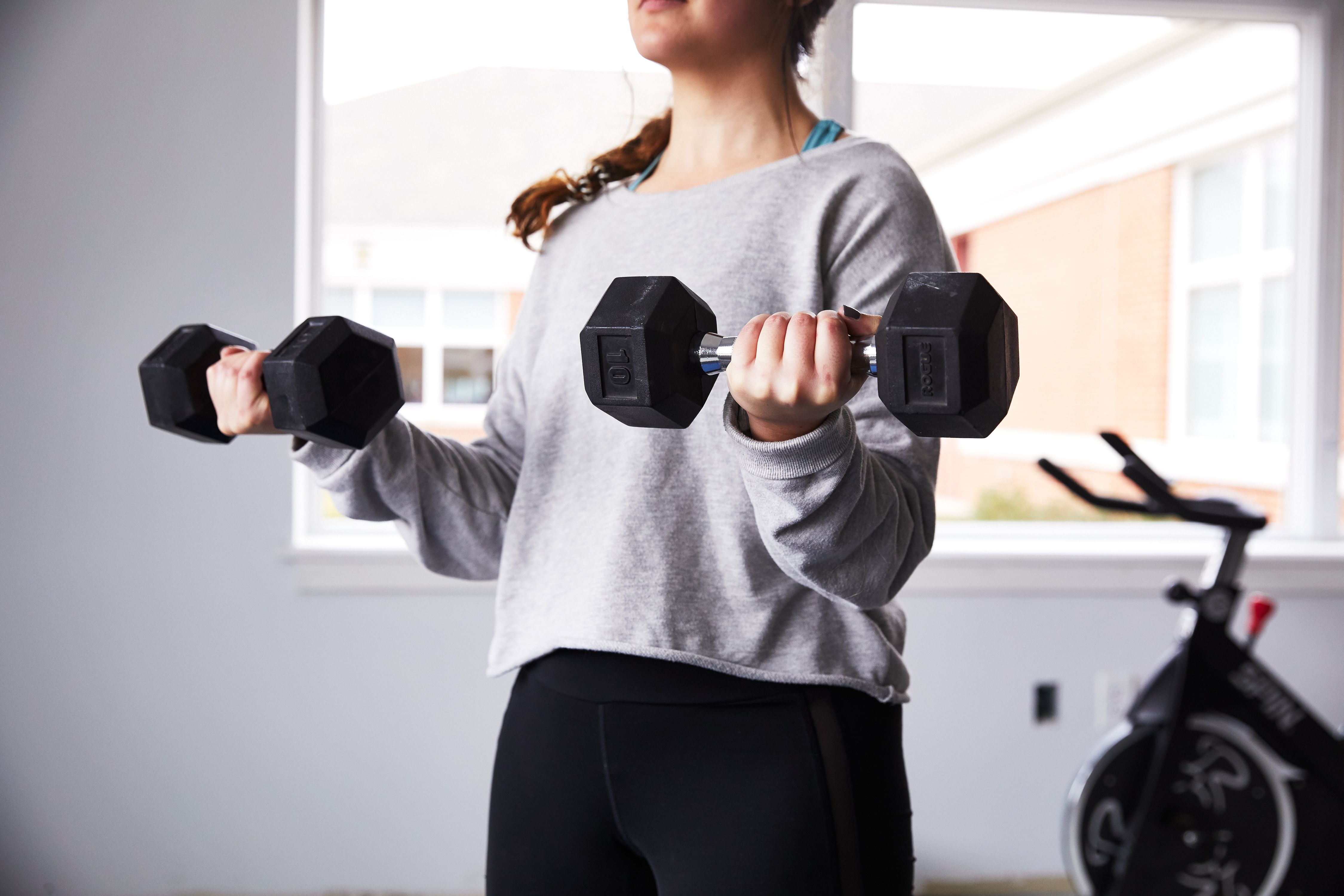 Woman exercise with dumbbells and working on her biceps at gym stock photo  - OFFSET