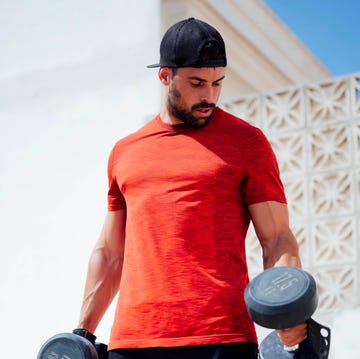 muscular young man lifting weights outside