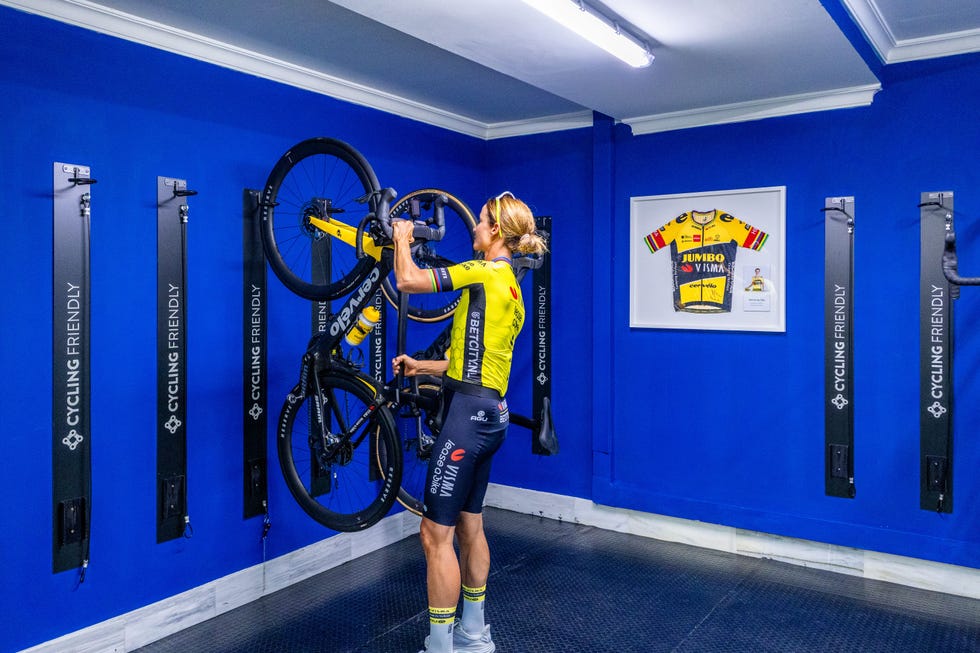 a cyclist placing a bicycle onto a wallmounted rack in a blue room
