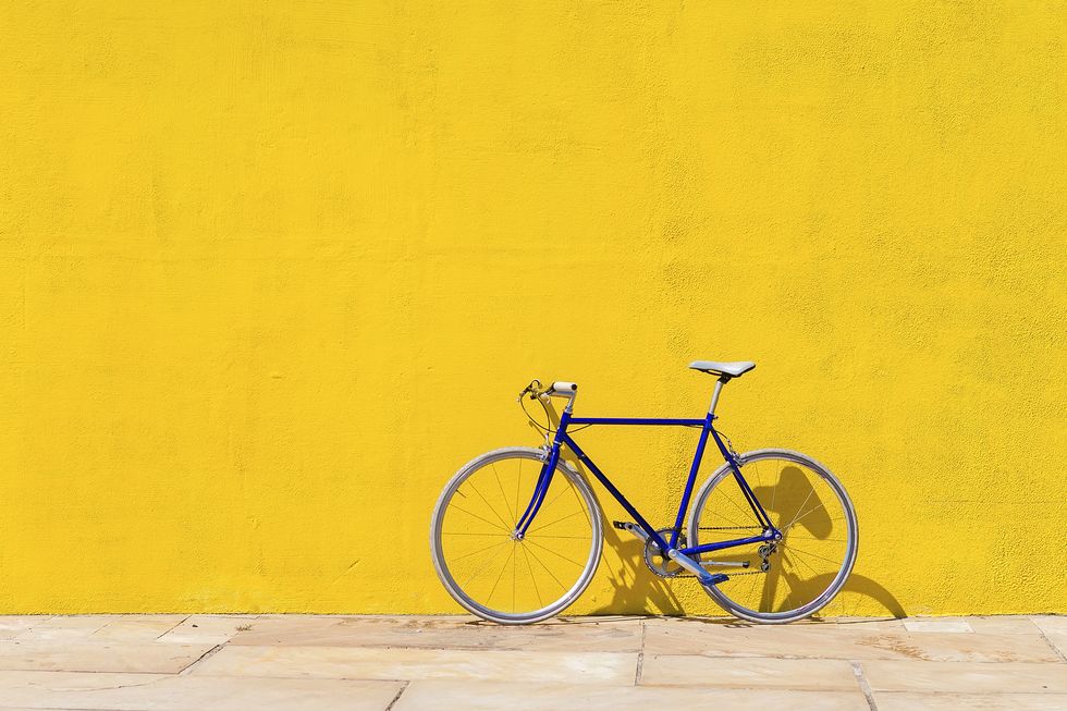 bicycle parked on sidewalk by wall during sunny day