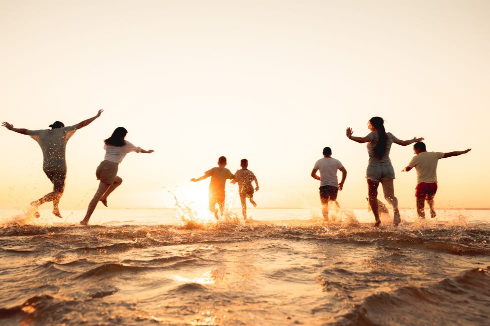 big group of friends or big family run at sunset beach