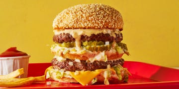 two patties stacked between three buns with melted cheese, lettuce, onions, and special sauce