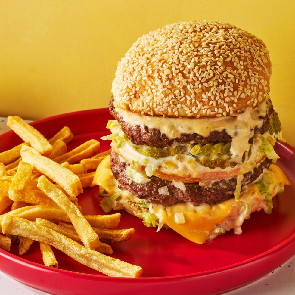 two patties stacked between three buns with melted cheese, lettuce, onions, and special sauce