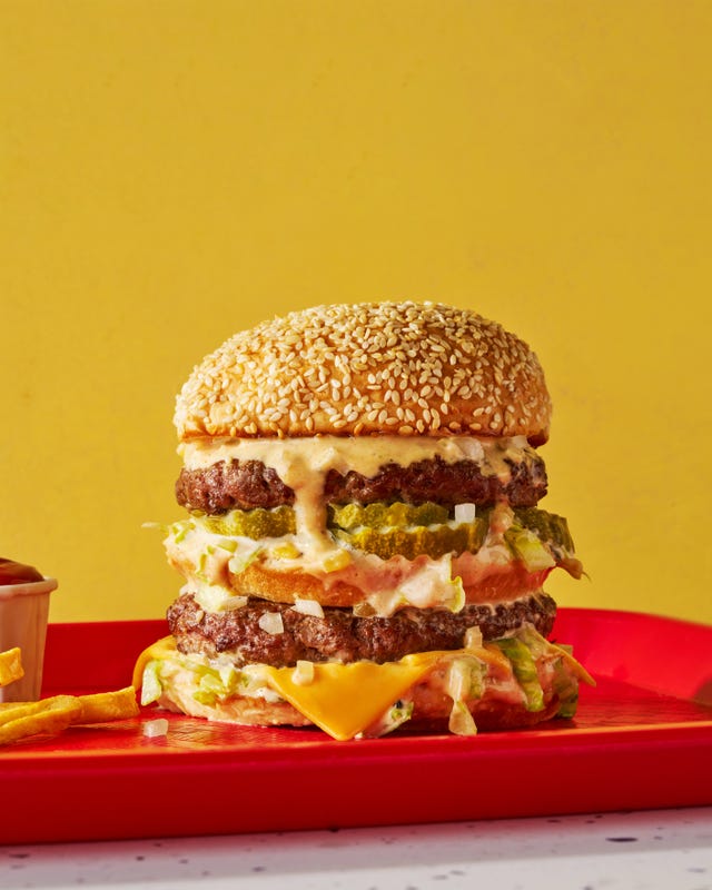 two patties stacked between three buns with melted cheese, lettuce, onions, and special sauce
