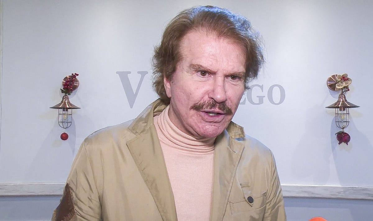 edmundo arrocet con un jersey de cuello alto en color crema y chaqueta beige