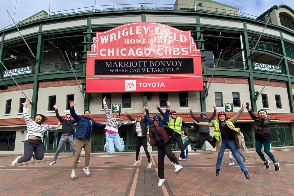 a group of people jumping in the air in front of wrigley field in chicago