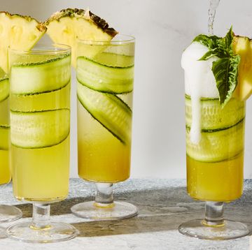 cucumber in a pineapple juice and prosecco cocktail garnished with a pineapple wedge
