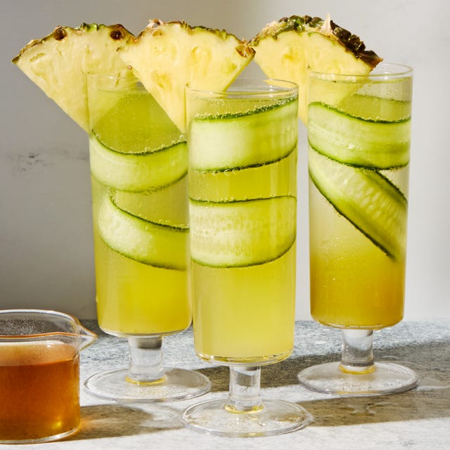 cucumber in a pineapple juice and prosecco cocktail garnished with a pineapple wedge