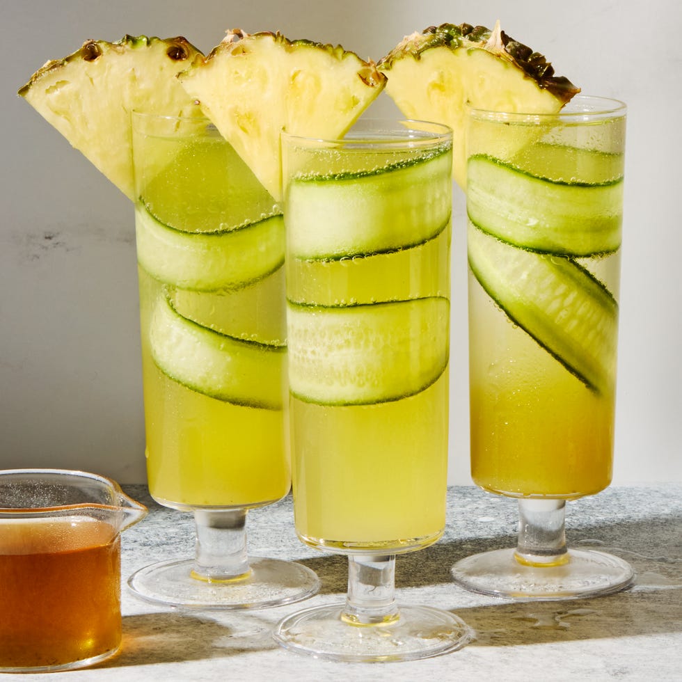 cucumber in a pineapple juice and prosecco cocktail garnished with a pineapple wedge