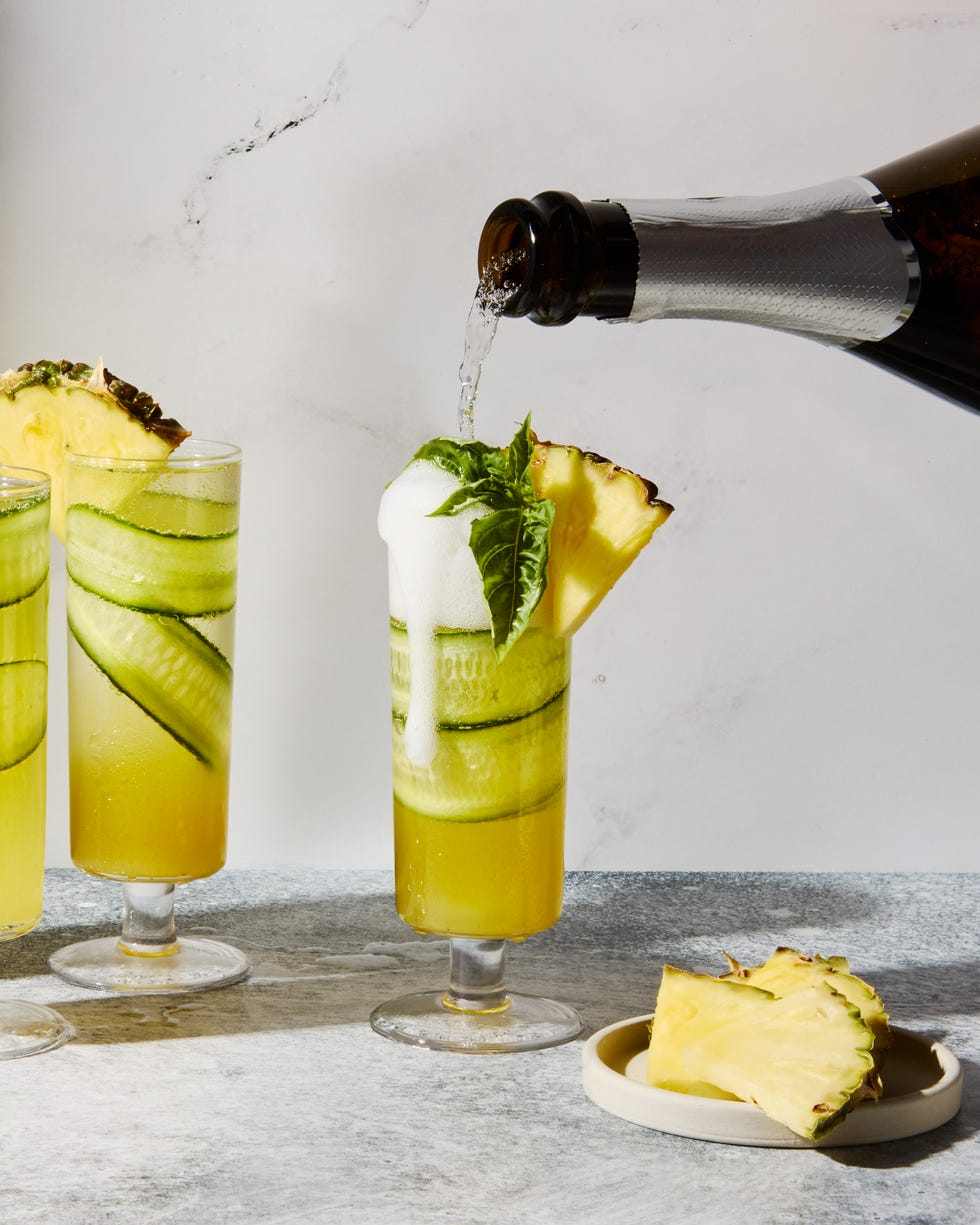 cucumber in a pineapple juice and prosecco cocktail garnished with a pineapple wedge
