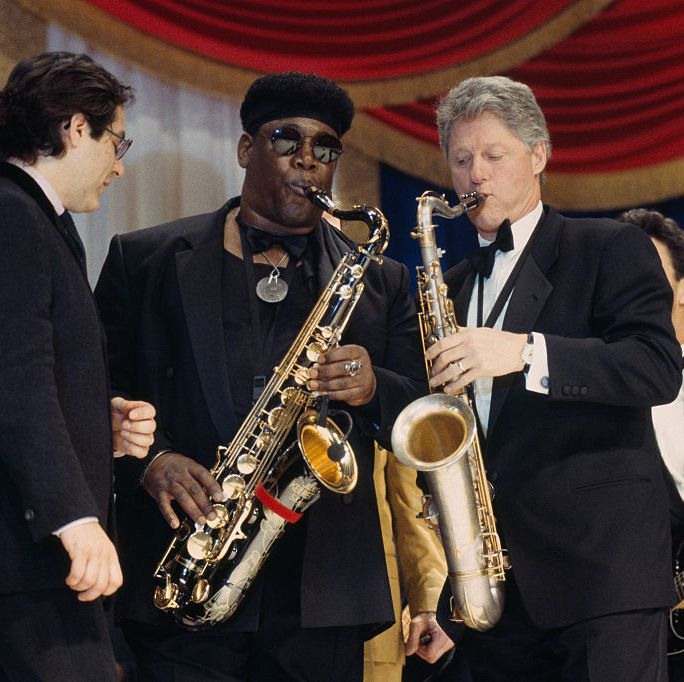 president bill clinton plays saxophone with musicians also playing around him