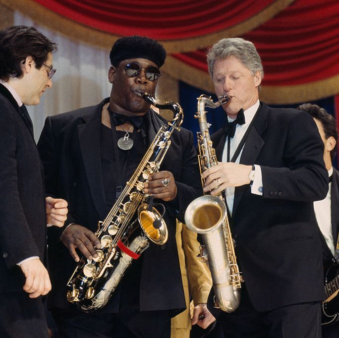 president bill clinton plays saxophone with musicians also playing around him