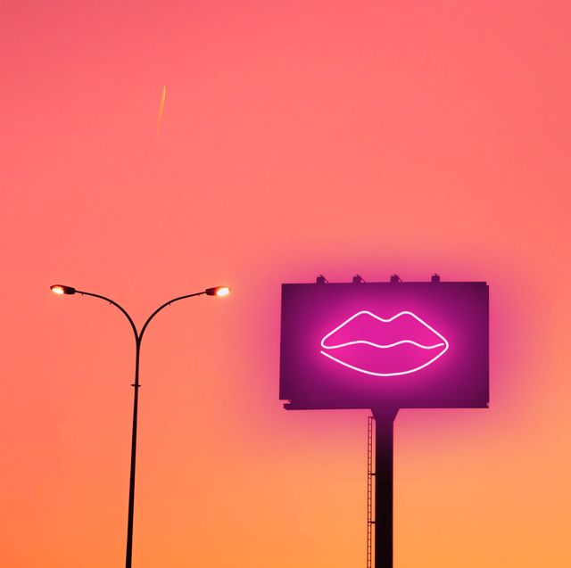 billboard with sexy lips neon light and sunset sky in the city