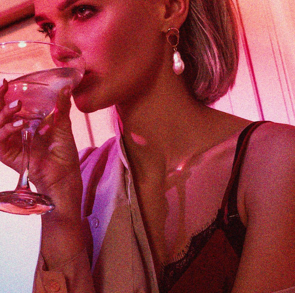 a woman in pink light drinking a cocktail