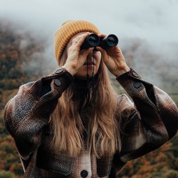 woman using binoculars in mountains