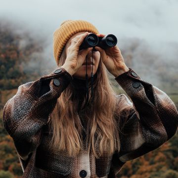 woman using binoculars in mountains