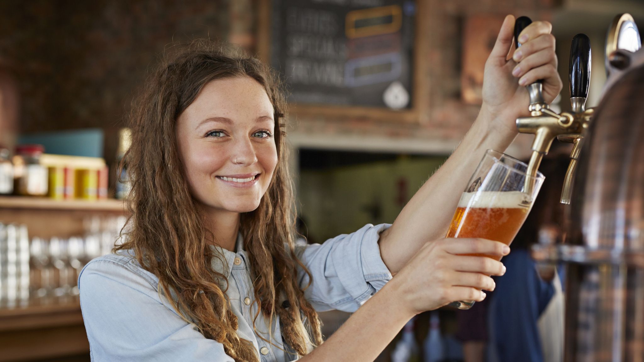 Portrait of bartender at microbrewery pouring beer