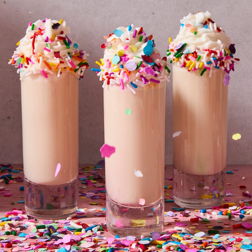 shot in a shot glass topped with sprinkles, whipped cream, and a candle