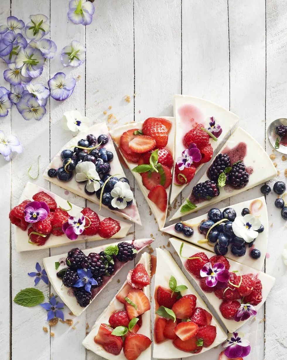 no bake cheesecake cut into slices with berry toppings and edible flowers