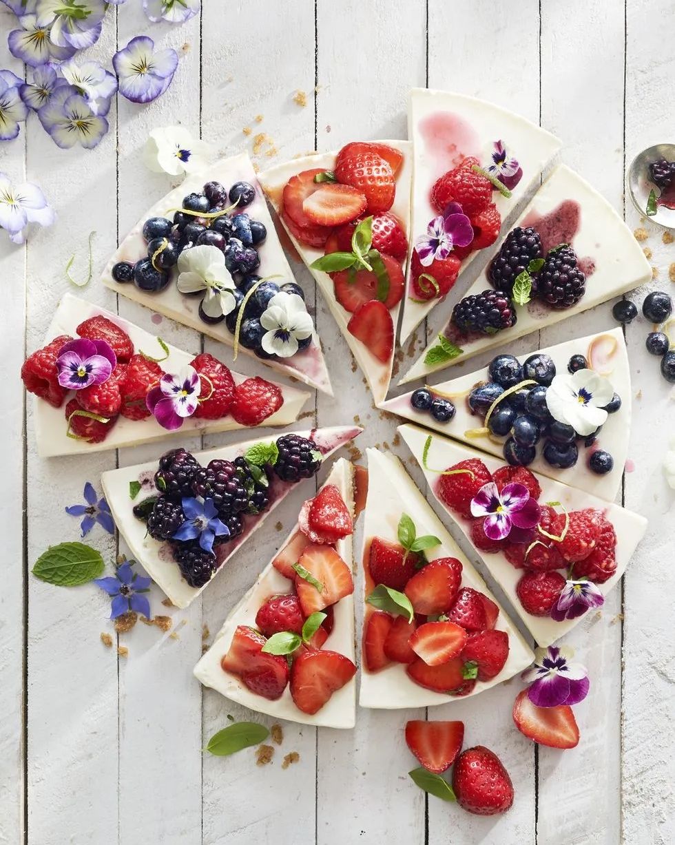 no bake cheesecake cut into slices with berry toppings and edible flowers