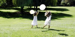 two girls running through field with balloons