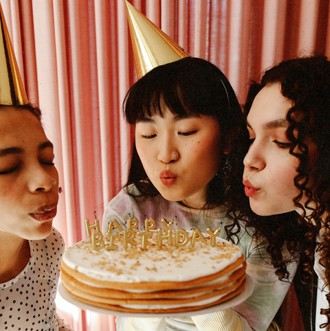 three girls blowing out birthday cake candles