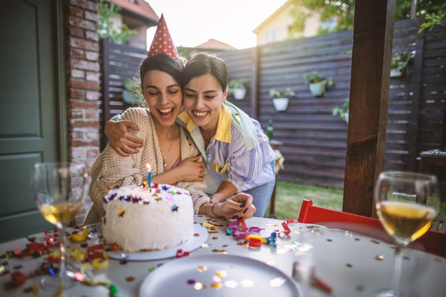 best friends enjoying a birthday party in a backyard with one young woman blowing out her birthday candle