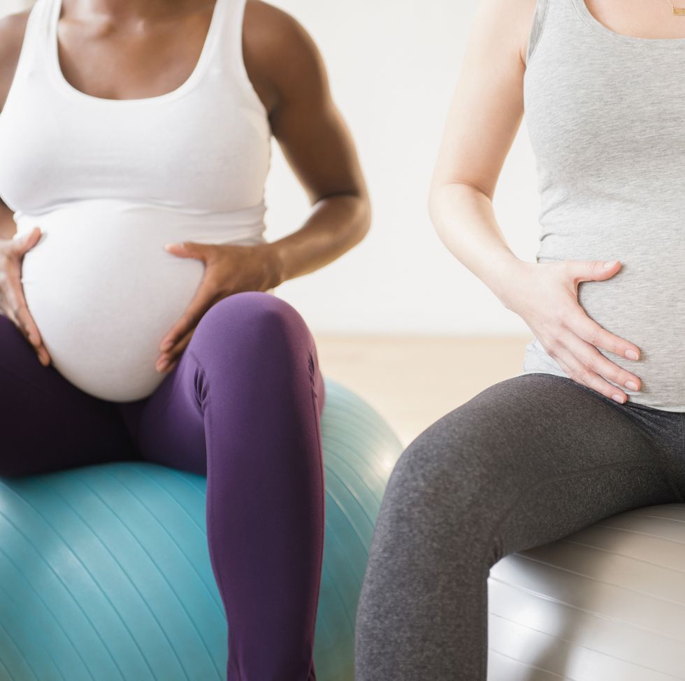 two pregnant women sitting on a birthing ball holding their bumps