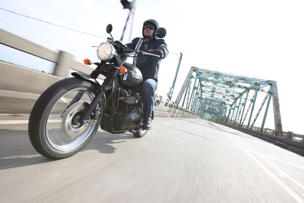 riding a triumph motorcycle across a bridge