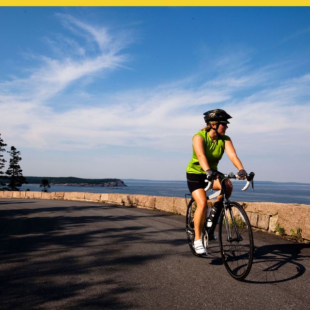 a female cyclist rides her road bike in maine's acadia national park