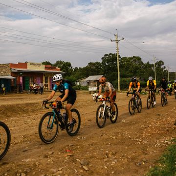 a group of cyclists riding on a dirt road