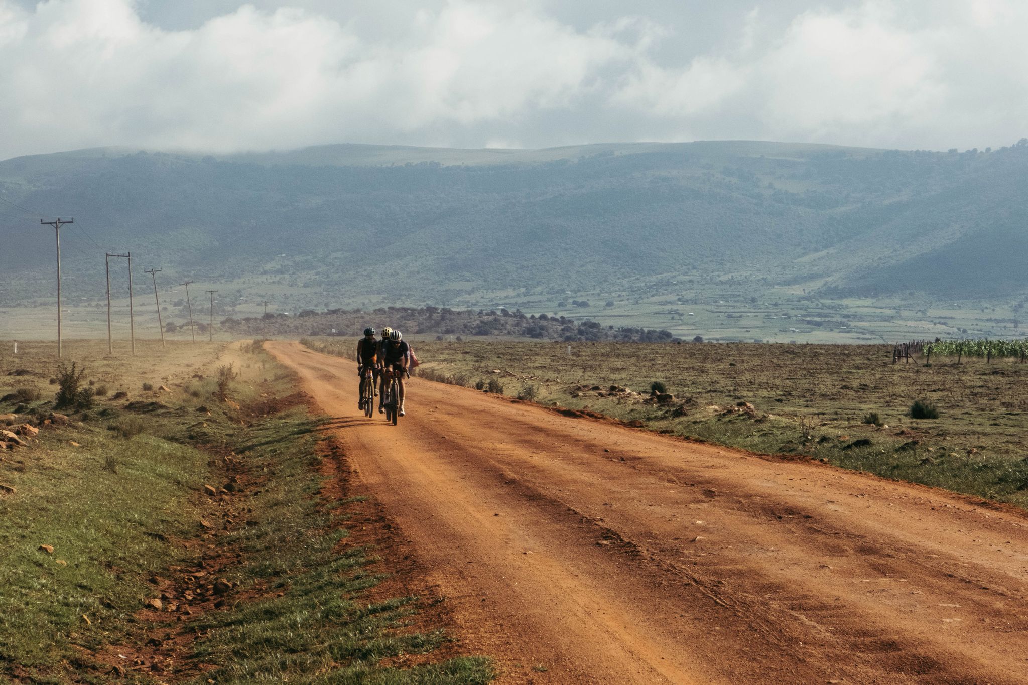 a group of cyclists riding on a dirt road