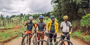 four cyclists on team amani pose for a portrait with their bikes while on a training ride on a gravel road outside iten kenya