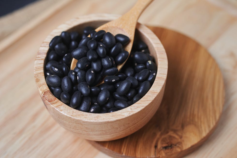 black beans in a wooden cup with a wooden spoon